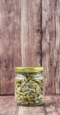 Kakule baharat yıpranmış ahşap arka plan üzerinde bir mason kavanoza