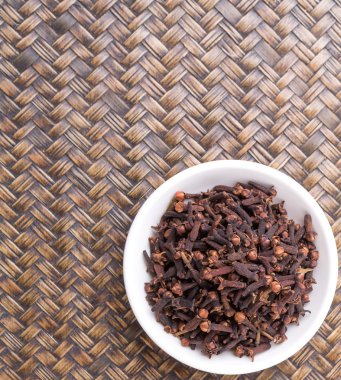 Karanfil baharat Hasır arka plan üzerinde beyaz bir kase