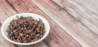 Karanfil baharat yıpranmış ahşap arka plan üzerinde beyaz kase