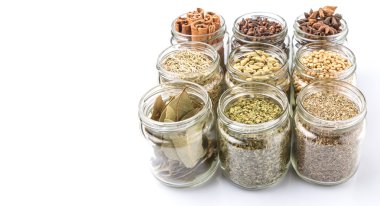 Kakule, Yıldız anason, tarçın, karanfil, kişniş tohumu baharat ve maydanoz, kekik, biberiye otlar mason kavanoz beyaz arka plan üzerinde