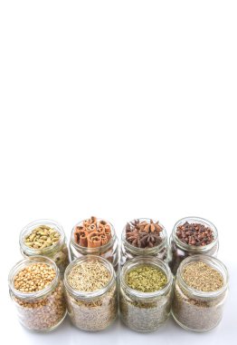 Kakule, Yıldız anason, tarçın, karanfil, kişniş tohumu baharat ve maydanoz, kekik, biberiye otlar mason kavanoz beyaz arka plan üzerinde