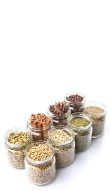 Kakule, Yıldız anason, tarçın, karanfil, kişniş tohumu baharat ve maydanoz, kekik, biberiye otlar mason kavanoz beyaz arka plan üzerinde