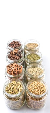 Kakule, Yıldız anason, tarçın, karanfil, kişniş tohumu baharat ve maydanoz, kekik, biberiye otlar mason kavanoz beyaz arka plan üzerinde