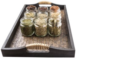 Kakule, Yıldız anason, tarçın, karanfil, kişniş tohumu baharat ve kurutulmuş defne yaprağı, maydanoz, kekik, biberiye otlar mason kavanoz hasır arka plan üzerinde