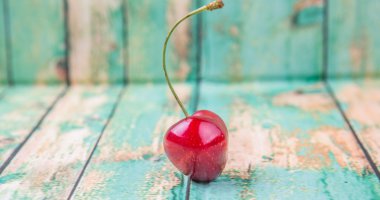 Kiraz meyve yıpranmış ışık yeşil ahşap arka plan üzerinde