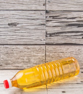 Ahşap arka plan üzerinde pişirme yağı bir plastik şişe sebze