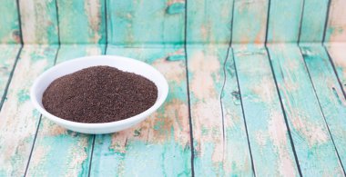 Rustik yıpranmış ahşap arka plan üzerinde beyaz kase kuru işlenmiş çay yaprakları