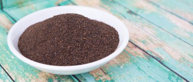 Rustik yıpranmış ahşap arka plan üzerinde beyaz kase kuru işlenmiş çay yaprakları