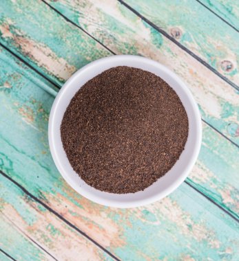 Rustik yıpranmış ahşap arka plan üzerinde beyaz kase kuru işlenmiş çay yaprakları