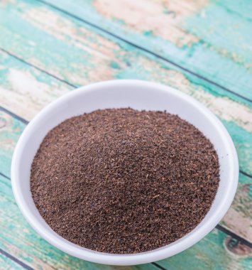 Rustik yıpranmış ahşap arka plan üzerinde beyaz kase kuru işlenmiş çay yaprakları