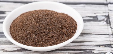 Rustik yıpranmış ahşap arka plan üzerinde beyaz kase kuru işlenmiş çay yaprakları