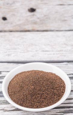 Rustik yıpranmış ahşap arka plan üzerinde beyaz kase kuru işlenmiş çay yaprakları