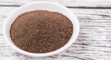 Rustik yıpranmış ahşap arka plan üzerinde beyaz kase kuru işlenmiş çay yaprakları