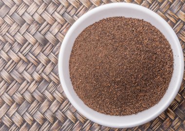 Rustik Hasır arka plan üzerinde beyaz kase kuru işlenmiş çay yaprakları