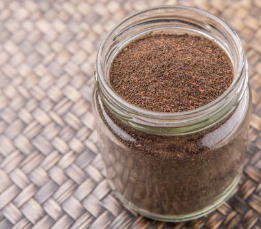 Kurutulmuş işlenmiş çay bir mason kavanoza rustik Hasır arka plan üzerinde bırakır.