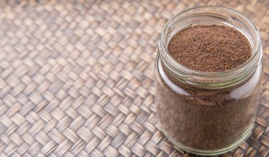 Kurutulmuş işlenmiş çay bir mason kavanoza rustik Hasır arka plan üzerinde bırakır.