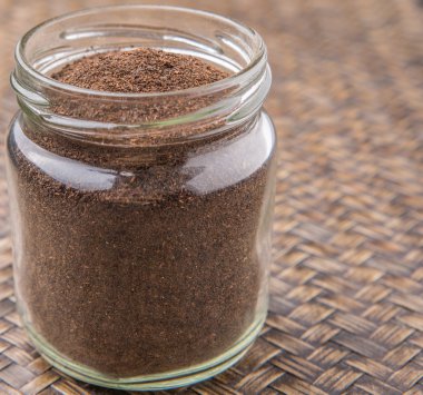 Kurutulmuş işlenmiş çay bir mason kavanoza rustik Hasır arka plan üzerinde bırakır.