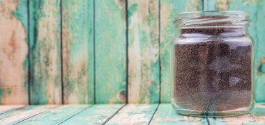 Kurutulmuş işlenmiş çay bir mason kavanoza rustik yıpranmış ahşap arka plan üzerinde bırakır.