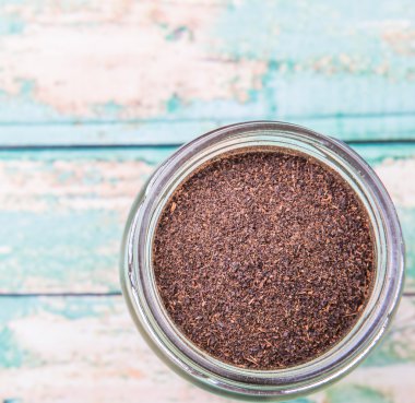 Kurutulmuş işlenmiş çay bir mason kavanoza rustik yıpranmış ahşap arka plan üzerinde bırakır.