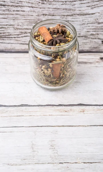 Mix herbs and spices in mason jar over weathered wooden background