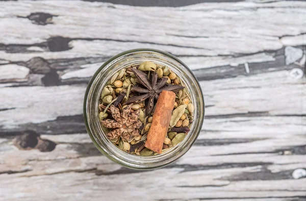 Mix herbs and spices in mason jar over weathered wooden background