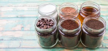 Kahve çekirdekleri, kahve tozu, krema, kakao tozu, bal ve işlenmiş çay yaprakları bir mason kavanoza yıpranmış ahşap arka plan üzerinde