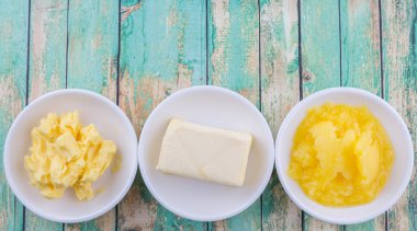 Tereyağı, margarin ve ghee rustik ahşap arka plan üzerinde beyaz kase bloğu