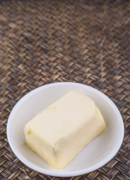 Кусок Масла Белой Миске Плетеном Фоне — стоковое фото