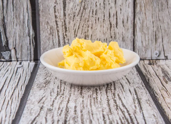 A bowl of margarine in white bowl over wooden background