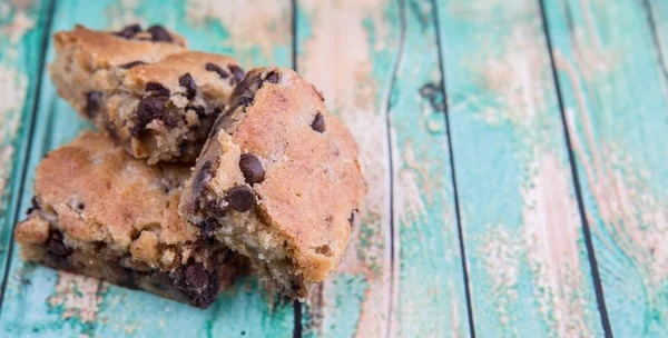 Sweet brownie dessert bar with chocolate chips over wooden background