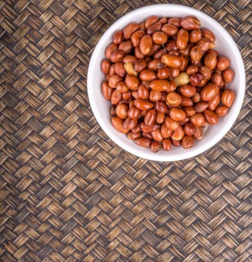 Derin kızarmış fıstık rustik Hasır arka plan üzerinde beyaz kase