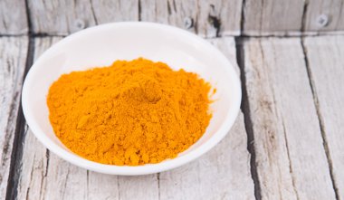 Zerdeçal tozu rustik ahşap arka plan üzerinde beyaz kase