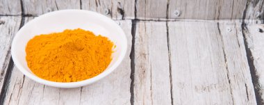 Zerdeçal tozu rustik ahşap arka plan üzerinde beyaz kase