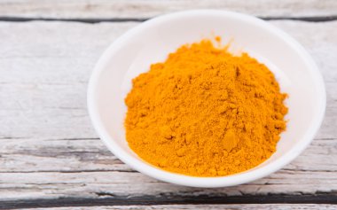 Zerdeçal tozu rustik ahşap arka plan üzerinde beyaz kase