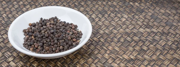 Peppercorn negro en tazón blanco — Foto de Stock