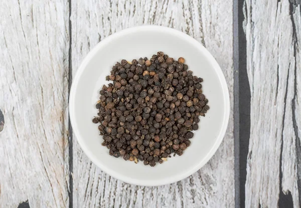 Peppercorn negro en tazón blanco — Foto de Stock