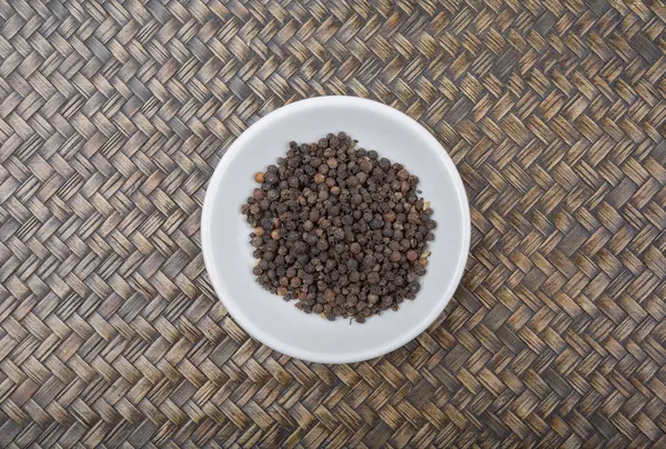 Peppercorn negro en tazón blanco — Foto de Stock