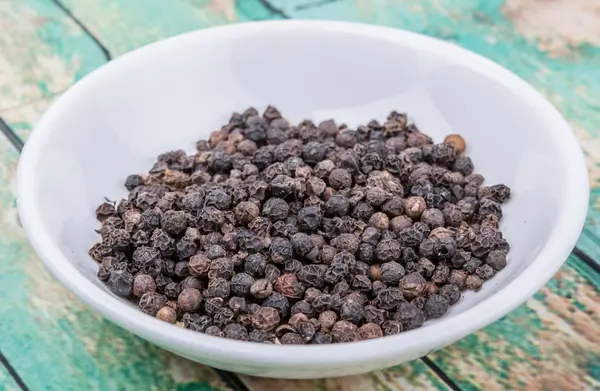 Peppercorn negro en tazón blanco — Foto de Stock