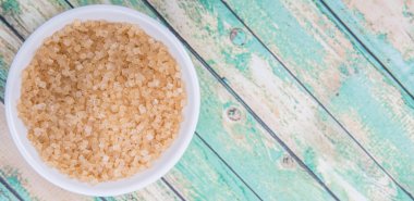 Kahverengi şeker ahşap arka plan üzerinde beyaz kase