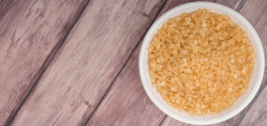 Kahverengi şeker ahşap arka plan üzerinde beyaz kase