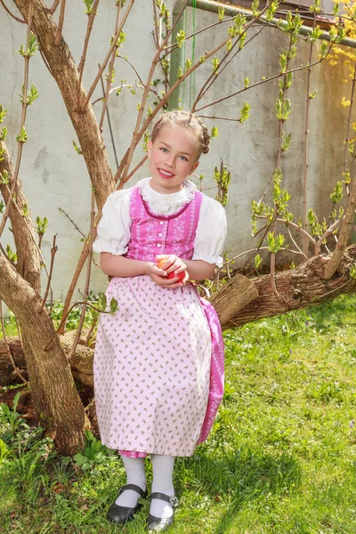 Girls in the dirndl sit in the garden and plays laughing with Easter eggs — Stock Photo, Image