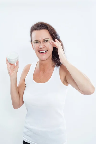 Brunette Woman Applying Eye Cream to Face — стокове фото