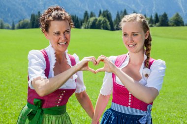 Dirndl elleri bir kalple oluşturan iki kadın