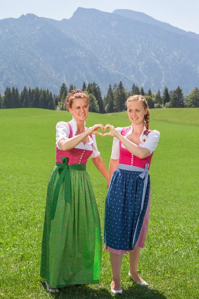 Zwei Frauen im Dirndl formen mit ihren Händen ein Herz — Stockfoto