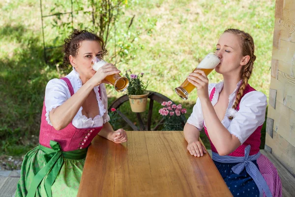 Beber Dos mujeres en Baviera Dirndl con una cerveza — Foto de Stock