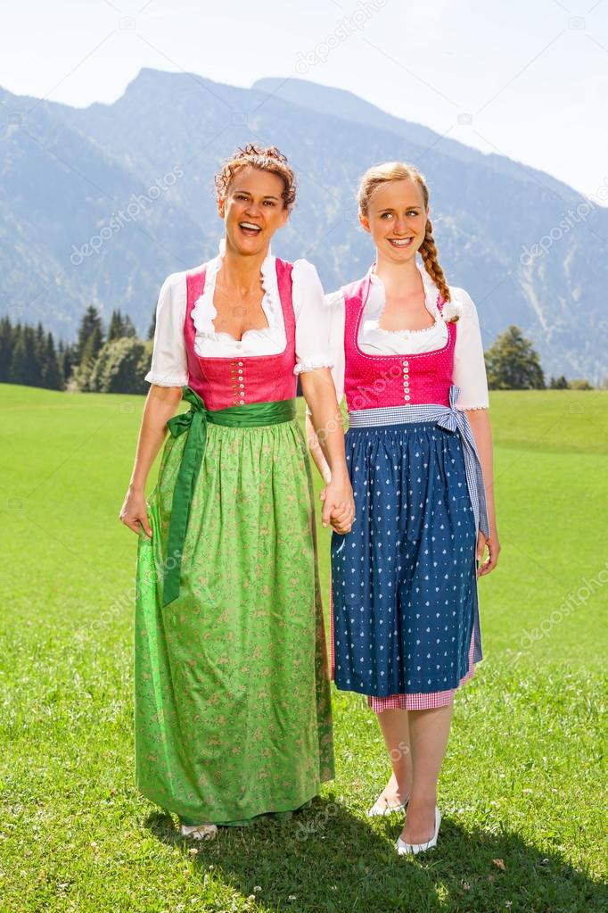 Mother and daughter walking both go hand in hand in a dirndl.