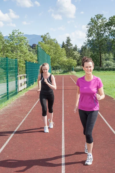 Due donne che corrono in pista insieme — Foto Stock