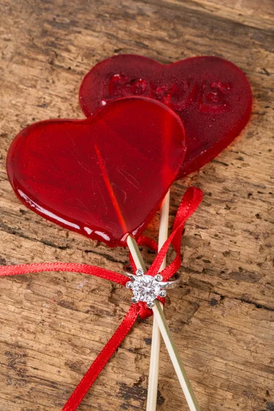 Anillo de diamantes con caramelos en forma de corazón en madera — Foto de Stock