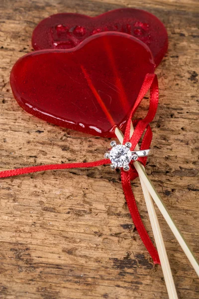 Anillo de diamantes con caramelos en forma de corazón en madera — Foto de Stock