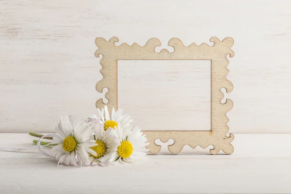 Fiori di margherita e una cornice vuota su sfondo di legno — Foto Stock